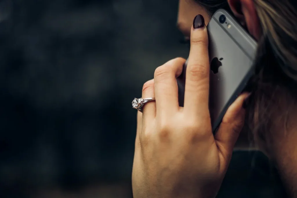 Woman on phone call, close-up of hand with ring holding smartphone